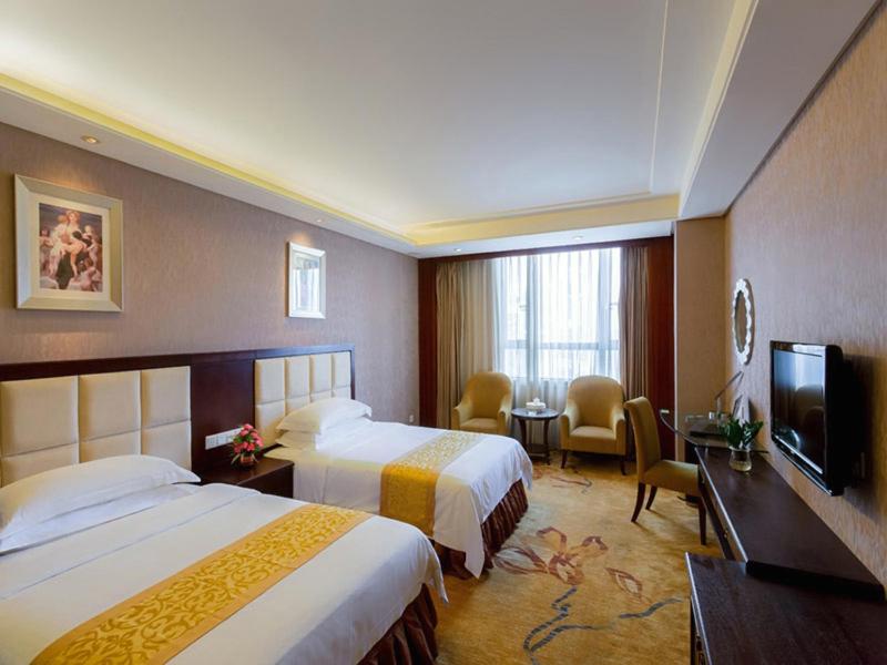 a hotel room with two beds and a flat screen tv at Vienna Hotel Lufeng Peopole Road in Lufeng