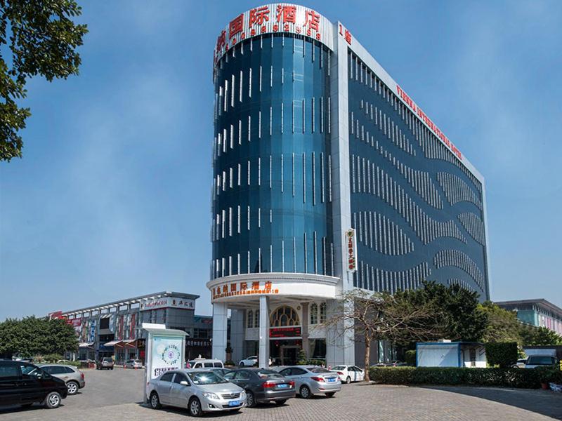 a large building with cars parked in front of it at Vienna International Hotel Shenzhen Hua'nan City in Longgang