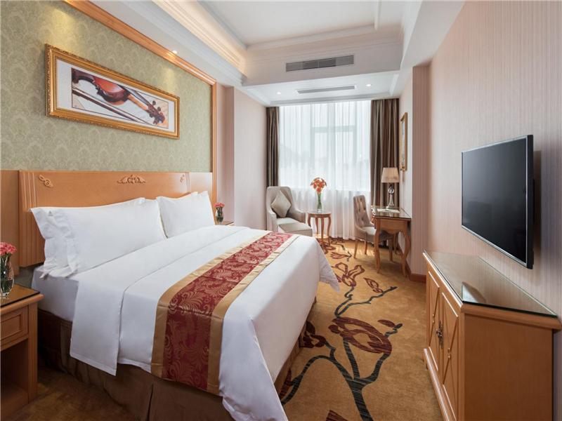 a hotel room with a bed and a flat screen tv at Vienna Hotel Tianbao Road in Shenzhen