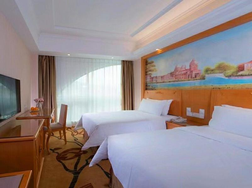una camera d'albergo con due letti e un dipinto sul muro di Vienna Hotel Shenzhen Dalang Clothing Base a Bao'an