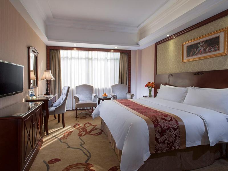 um quarto de hotel com uma cama grande e uma televisão em Vienna Hotel Shaoguan Wujiang Kuangshan Park em Shaoguan