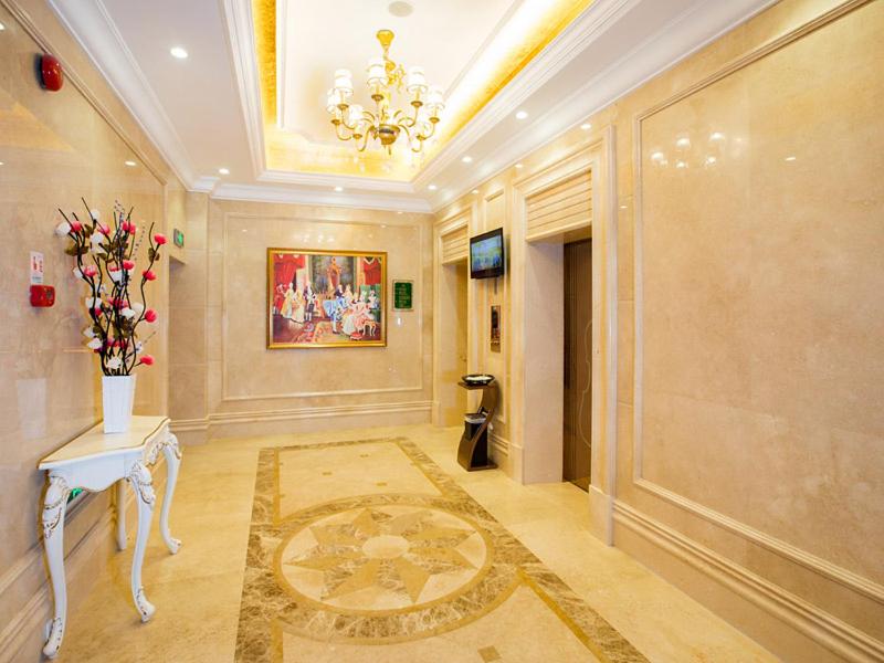 恵州市にあるVienna Hotel Huizhou Dahuxiのテーブルと花瓶のある広い客室です。