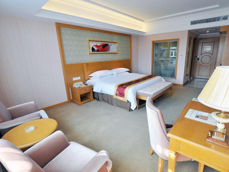 Habitación de hotel con cama, mesa y sillas en Vienna Hotel Qidong South Gongyuan Road en Qidong