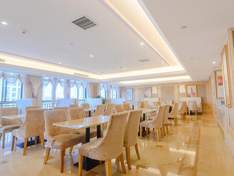 a dining room with tables and chairs and windows at Vienna International Hotel Hengyang Chuanshan Road Branch in Hengyang