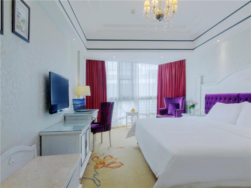 a bedroom with a bed and a desk with a television at Vienna Hotel Guilin Exposition Center in Guilin