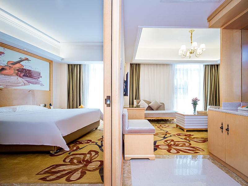 um quarto de hotel com uma cama e uma sala de estar em Vienna Hotel Whhan xingye road stone bridge subway station store em Wuhan