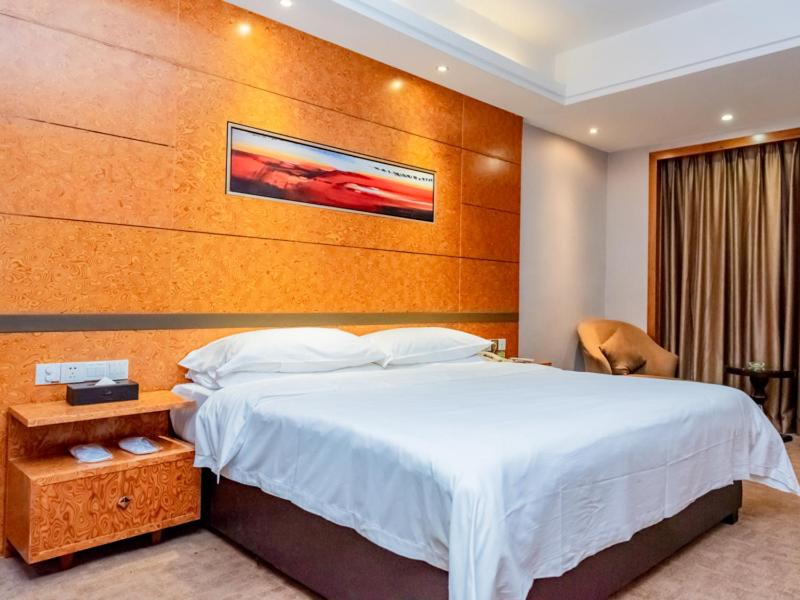 1 dormitorio con 1 cama grande y cabecero de madera en Vienna Hotel Dongguan Tangxia Binfen Plaza en Dongguan