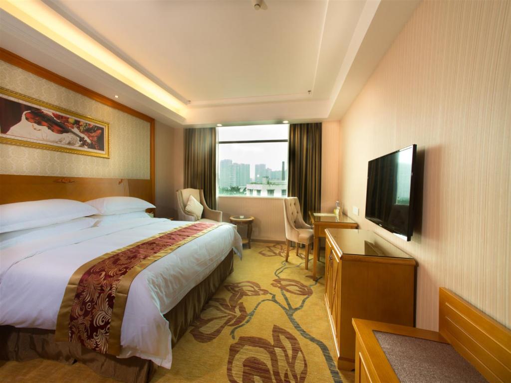 a hotel room with a bed and a flat screen tv at Vienna Hotel Guangzhou Songnan in Guangzhou