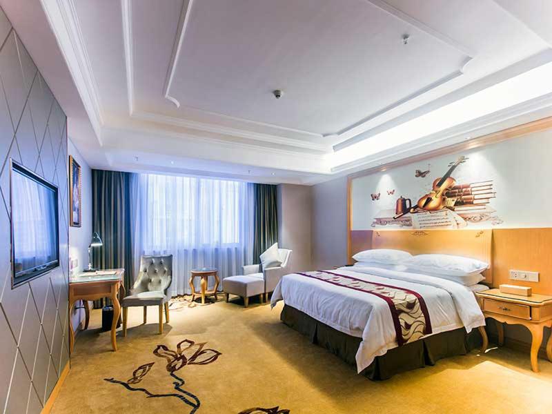 een hotelkamer met een groot bed en een bureau bij Vienna International Hotel Haikou West Bus Station in Haikou
