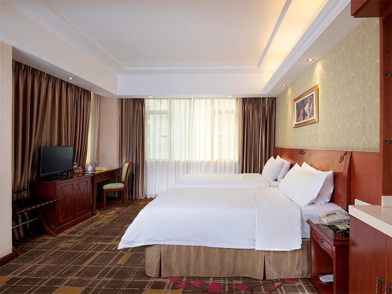 a hotel room with a large bed and a television at Vienna Hotel Dongguan Hou street Wanda Plaza in Dongguan