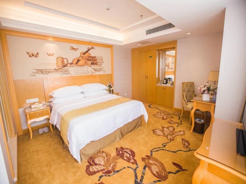 a hotel room with a bed and a painting on the wall at Vienna Hotel Guangdong Huizhou Jiangbei Sanxin in Huizhou