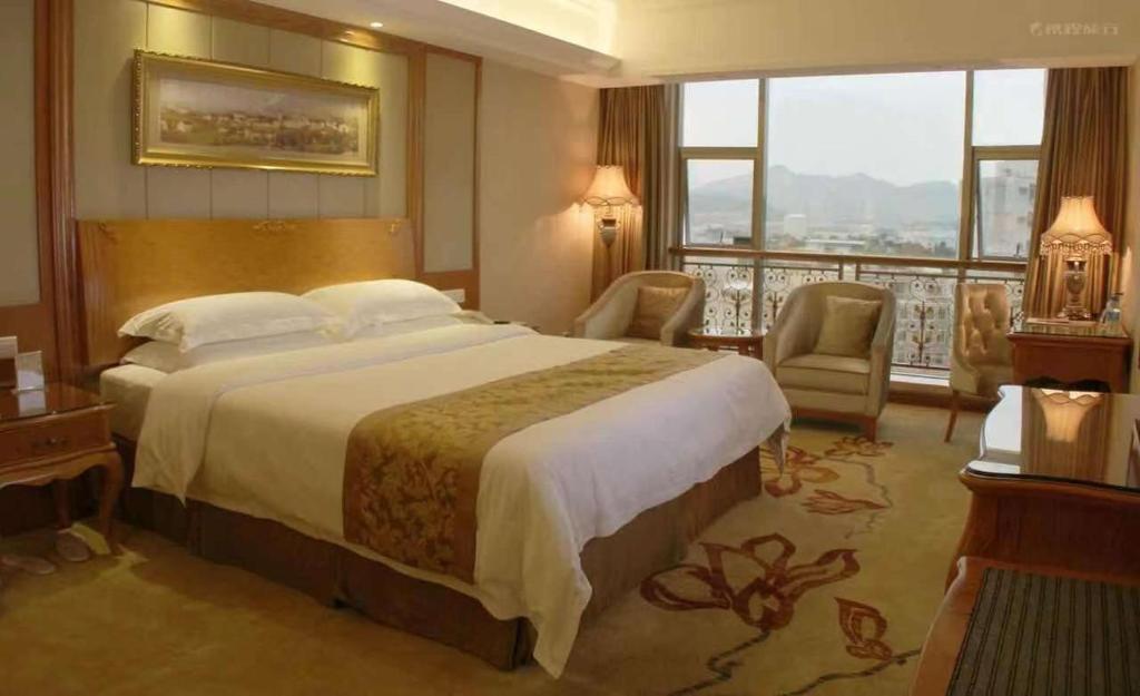 ShanweiにあるVienna Hotel Shanwei Chengqu Xingye Roadの大きなベッドとバルコニーが備わるホテルルームです。