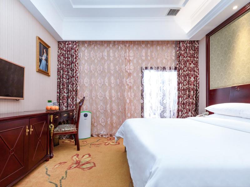 a bedroom with a bed and a desk and a window at Vienna Hotel Shanghai Songjiang Wanda in Songjiang