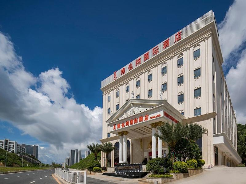 a large white building with a sign on it at Vienna International Hotel Shenzhen Bantian Jihua Road Shangxue in Longgang