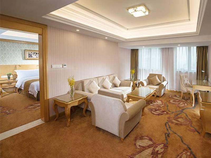 um quarto de hotel com um sofá e uma cama em Vienna Hotel Longchuan em Longchuan