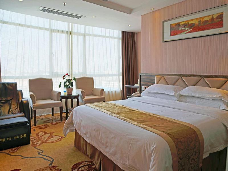 een slaapkamer met een groot bed en stoelen in een kamer bij Vienna 3 Best Hotel Dongguan Shida Road in Liaobu