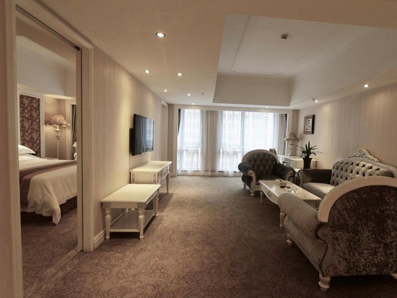 a hotel room with a bed and a living room at Vienna International Hotel Jieyang People's Avenue in Jieyang