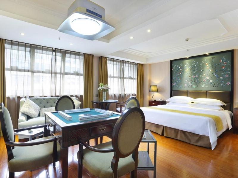 a hotel room with a bed and a table and chairs at Vienna Hotel Changsha Gaoxin Lugu Park in Changsha