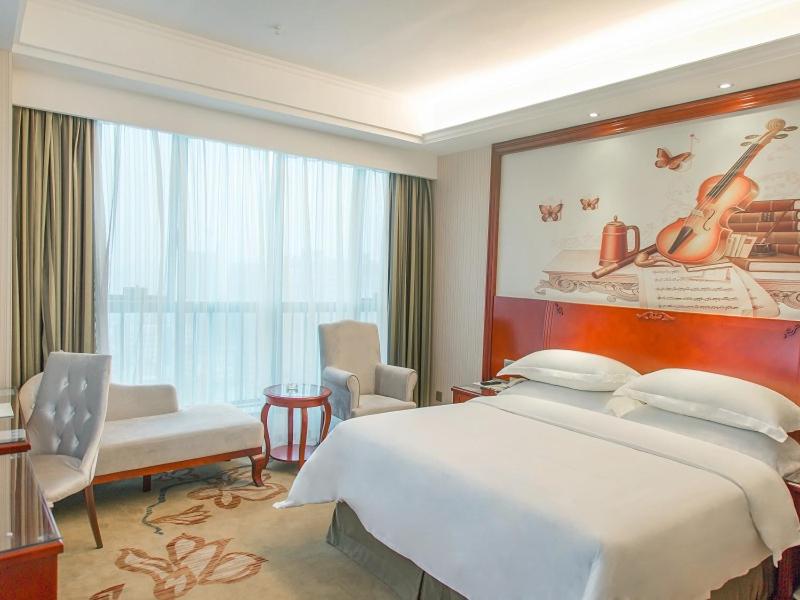 a hotel room with a large bed and a large window at Vienna Hotel Jian People Square in Ji'an