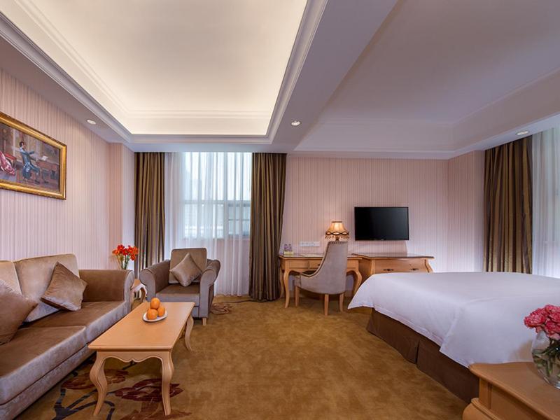 una camera d'albergo con letto, divano e scrivania di Vienna International Hotel Shenzhen Longhua Center a Bao'an