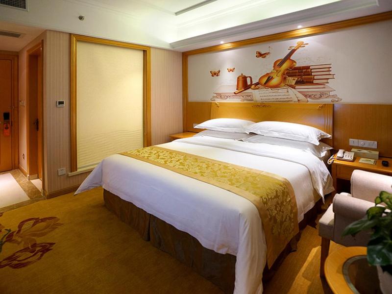 a bedroom with a large bed with a violin on the wall at Vienna Hotel Shanghai Hongqiao National Exhibition Center Huaxin in Qingpu