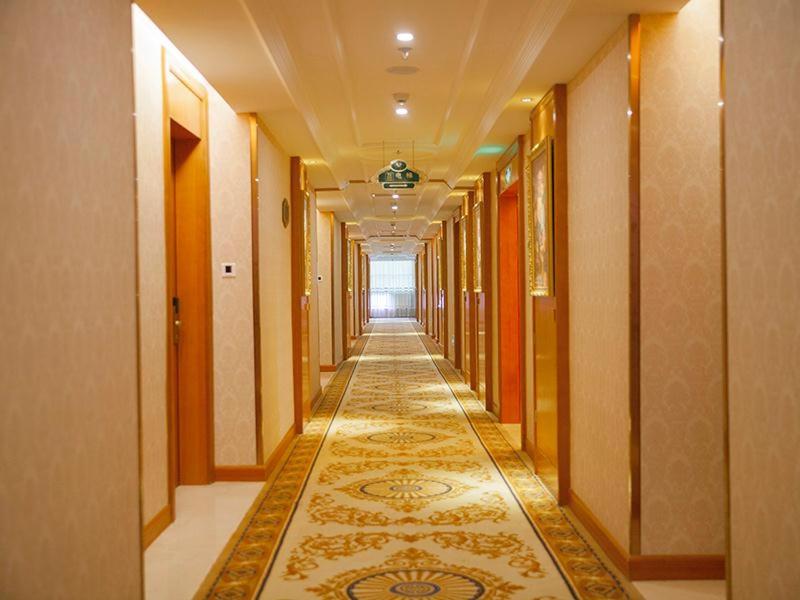 un pasillo de un edificio con una alfombra en el suelo en Vienna Hotel Ganzhou Anyuan en Tieshan