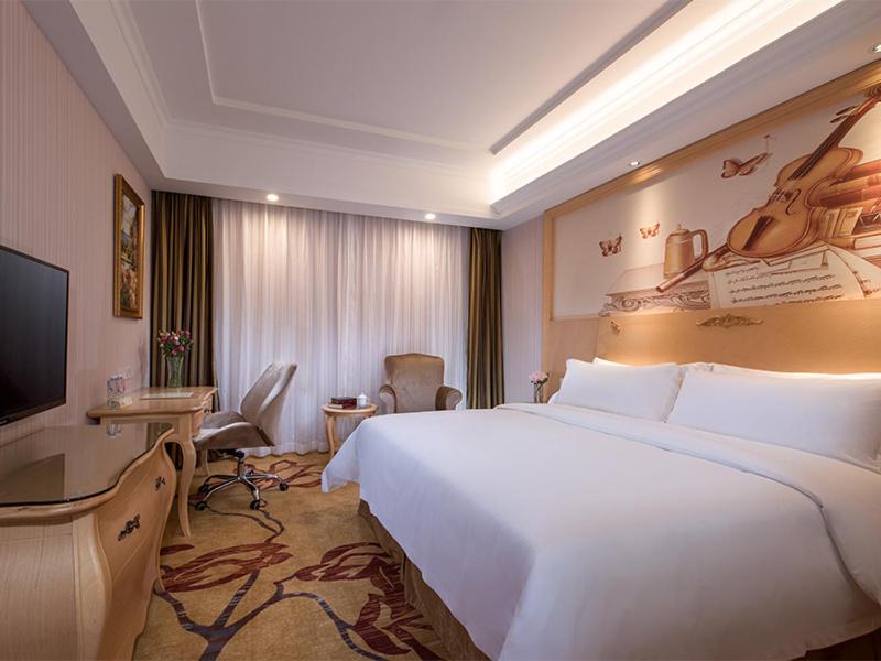 una camera d'albergo con un grande letto bianco e una TV di Vienna Hotel Shenzhen North Science And Technology Park a Shenzhen
