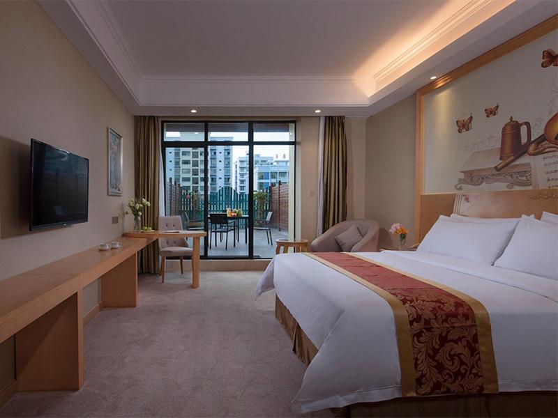 a hotel room with a large bed and a balcony at Vienna Hotel (Qionghai Yinhai Road) in Qionghai