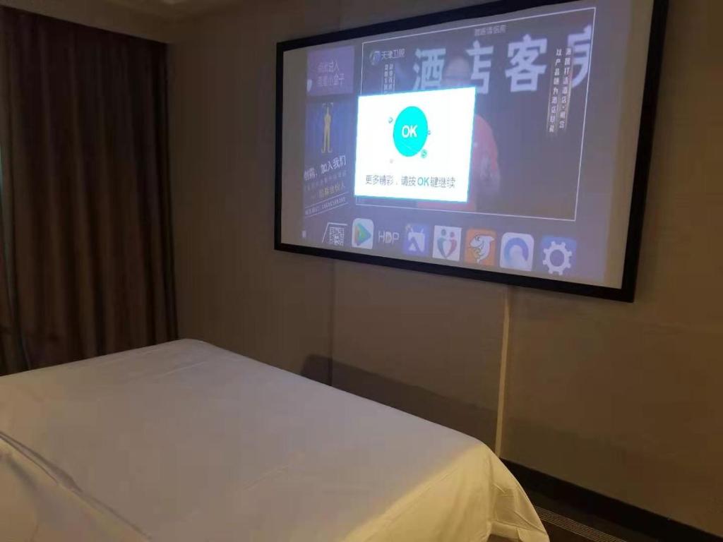 a projection screen in a room with a bed at Vienna International Hotel Changzhou Railway Station in Changzhou