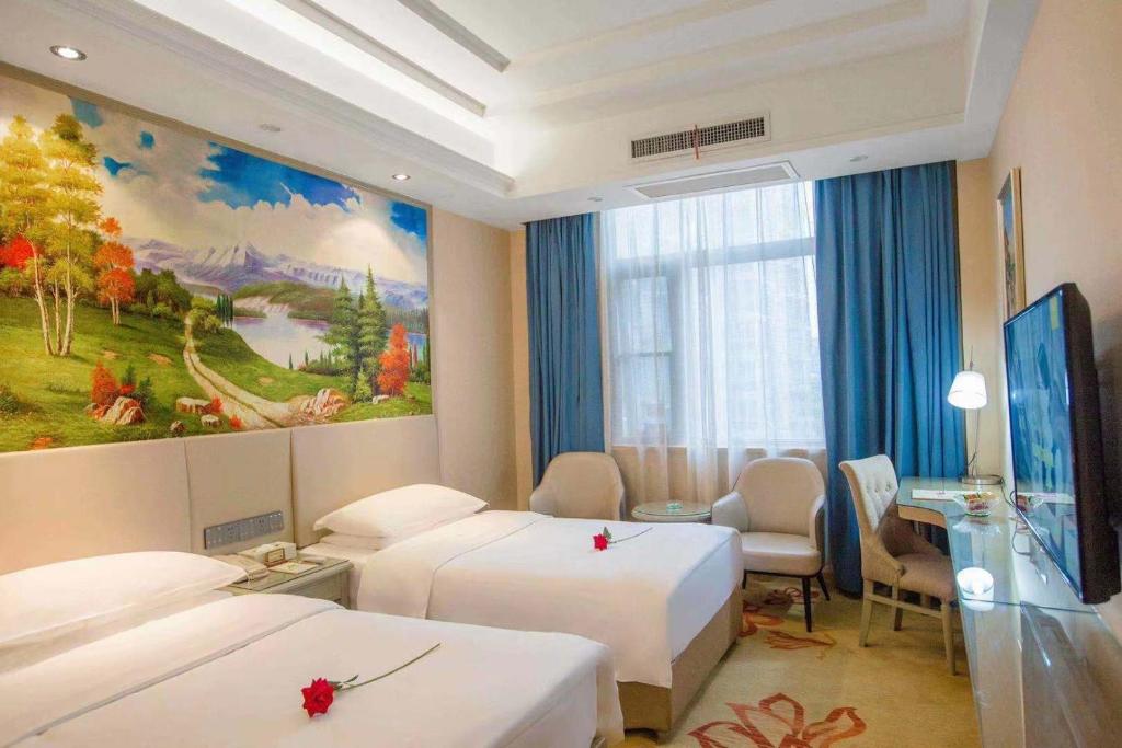 a hotel room with two beds and a painting on the wall at Vienna Hotel Nanyang People Road in Nanyang