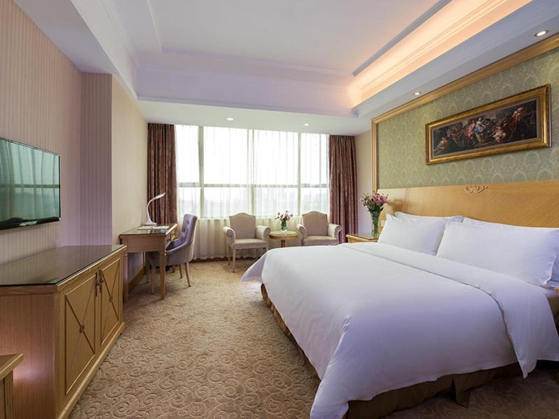 una camera d'albergo con un grande letto e una TV di Vienna Hotel Dongguan Tangxia Lincun Square a Dongguan