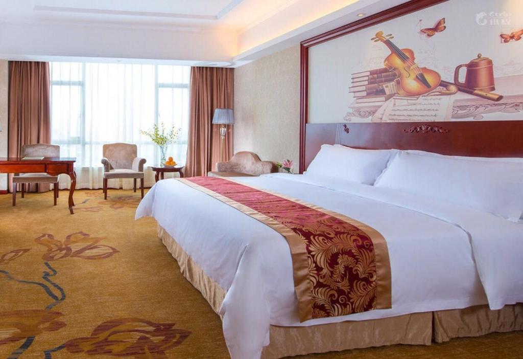 מיטה או מיטות בחדר ב-Vienna International Hotel Dongguan Chang'an North Station