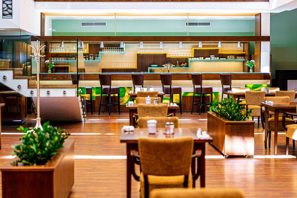 a restaurant with tables and chairs and a cafeteria at Hotel Baltaci Atrium in Zlín