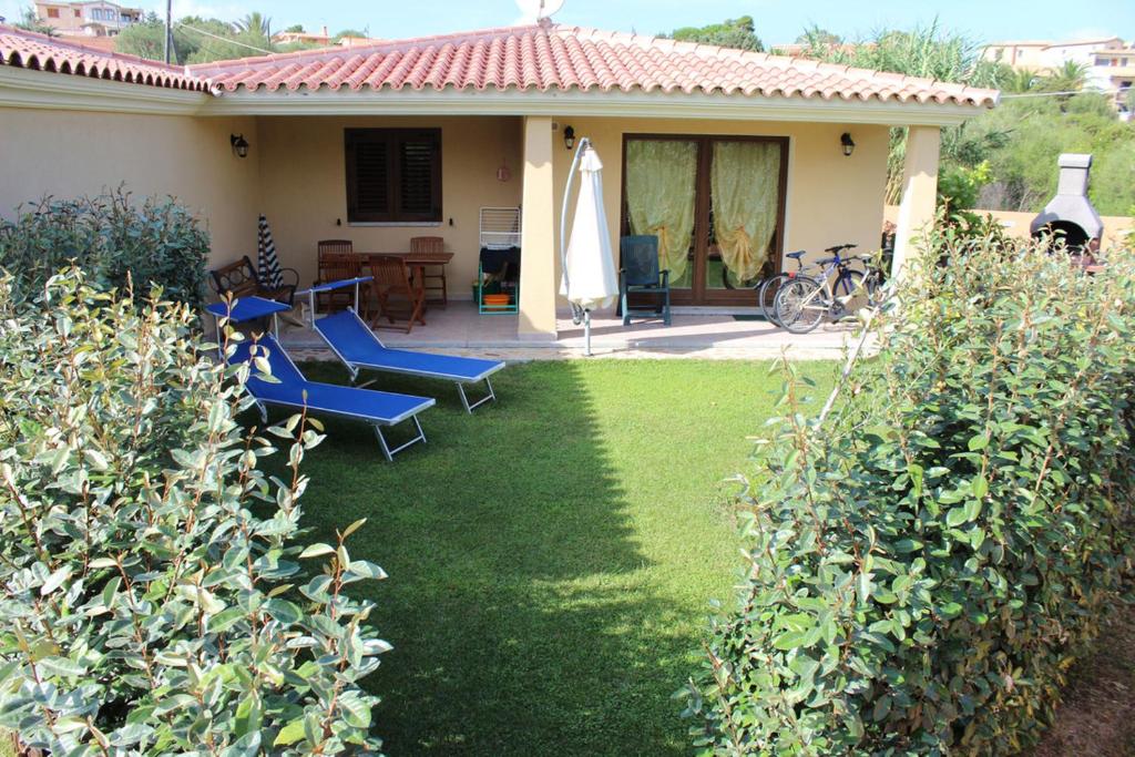 a house with a yard with chairs and a patio at CASADELFARO con Giardino a Pittulongu 600Metri dalla Spiaggia in Olbia