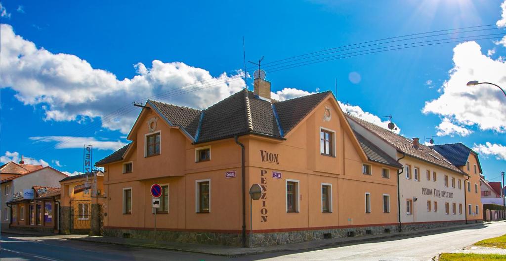 a brown building with a black roof on a street at Penzion Vion in Plzeň