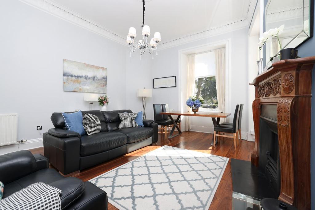 een woonkamer met een zwarte bank en een tafel bij ALTIDO Stunning Ground-floor 2 Bedroom New Town Apartment in Edinburgh