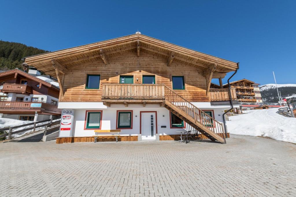 a large building with a wooden roof and a balcony at Sommer Chalet Hirsch für 6 Personen in Königsleiten
