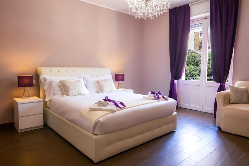 1 dormitorio con 1 cama con cortinas moradas y lámpara de araña en Arcobaleno Suites en Cagliari