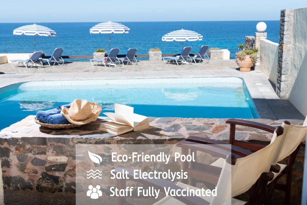 Porto Sisi Hotel Apartments في سيسي: مسبح ذو قبعة جالس بجوار المحيط