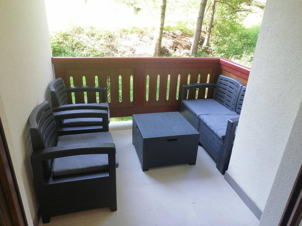 einen Balkon mit 2 Stühlen, einer Bank und einem Tisch in der Unterkunft Apartman Harmonija in Zlatibor