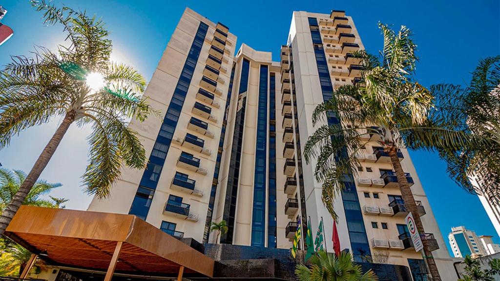a tall building with palm trees in front of it at STAY Sun Square in Goiânia