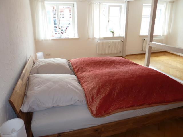a bedroom with a bed with a red blanket on it at Ferienwohnung - Mittendrin - in Wangen im Allgäu