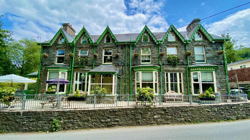 a green brick house with a stone wall at Hafan Artro in Llanbedr