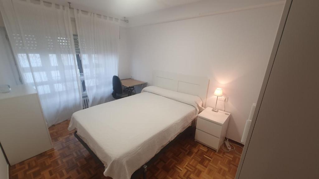 um pequeno quarto com uma cama branca e um candeeiro em Libertad 10, piso céntrico en Gijón, con WIFI de 3 hab para 5 personas em Gijón