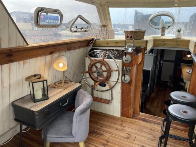 Exceptionnel bateau maison reine mathilde في اويسترهام: غرفة بها مكتب وكرسي في قارب