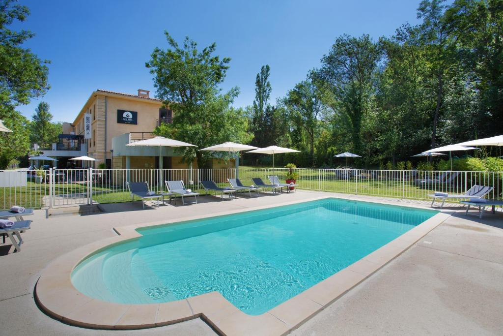 a swimming pool with chairs and umbrellas at Suite Home Aix en Provence Sud TGV in Bouc-Bel-Air