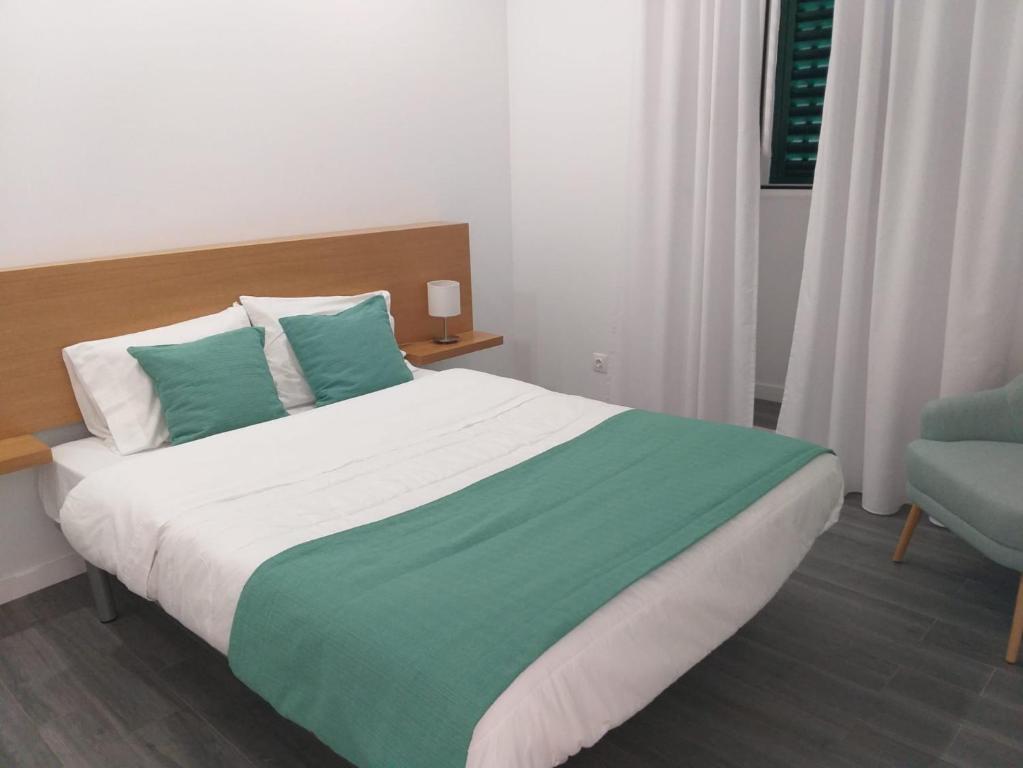 a bedroom with a large bed and a blue chair at Casa das Ondas in Ribeira Grande
