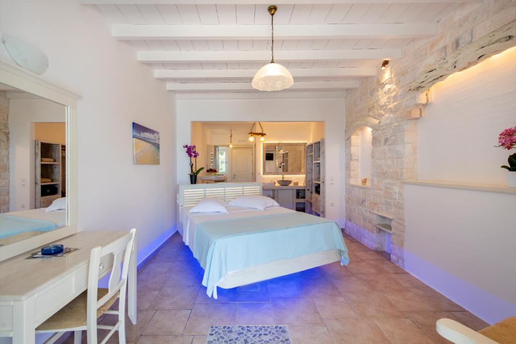 a bedroom with a bed and a desk and a kitchen at Akti Naoussa Paros in Naousa