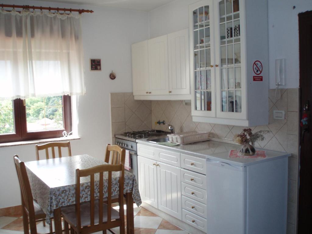 une cuisine avec des placards blancs et une table avec des chaises dans l'établissement Apartments Hiper, à Matulji