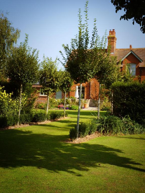 a garden with a house and a tree in the yard at Walwyn Court Barns in Ledbury